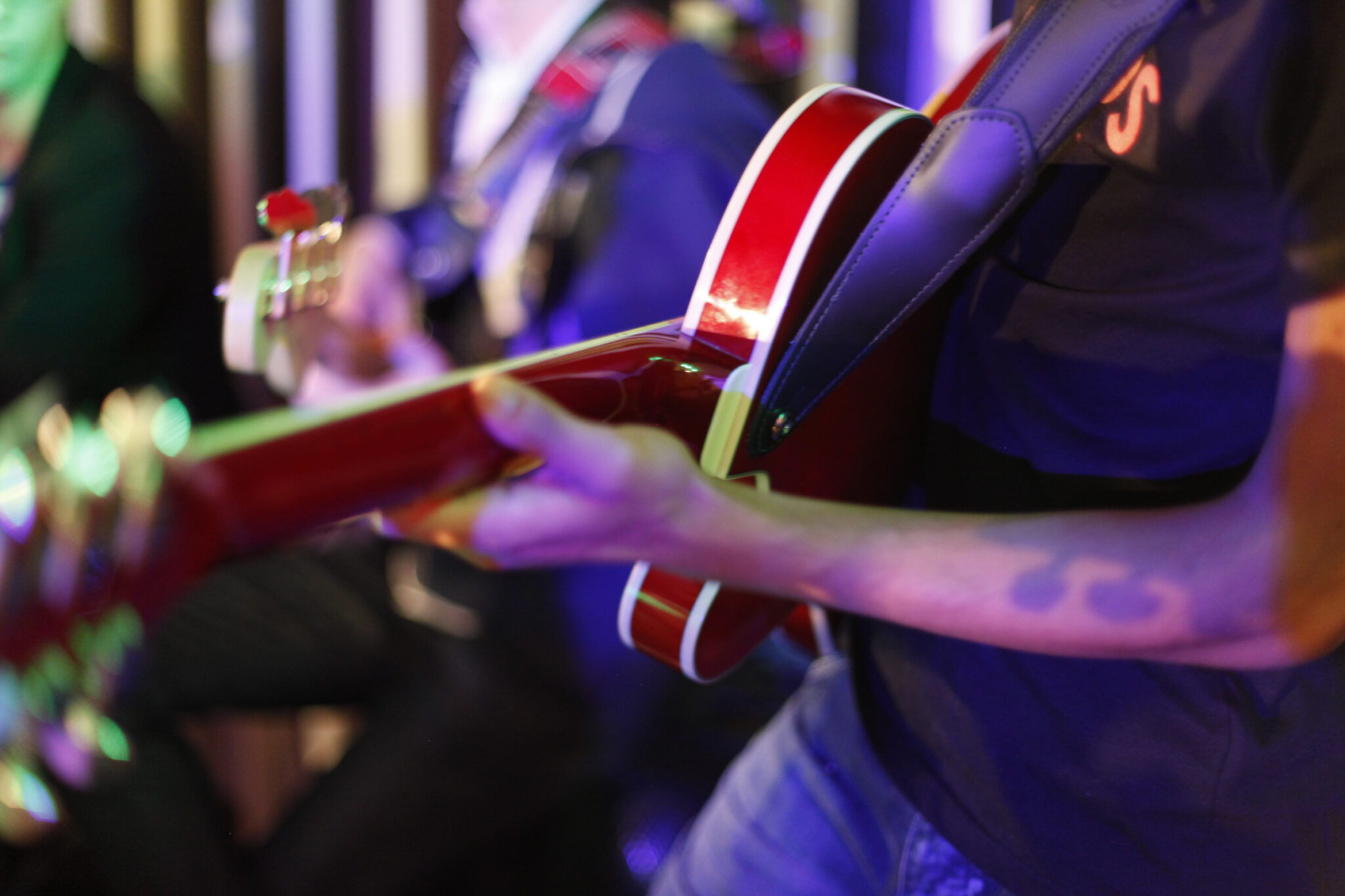 Bild på en arm som håller en röd gitarr och spelar.