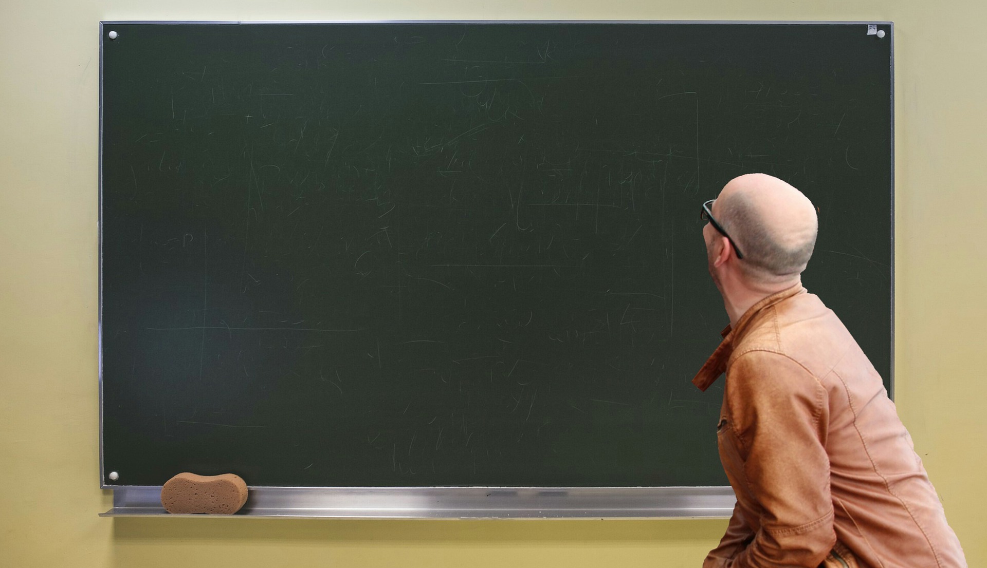 Syntolkning: En man står framför en svart tavla, han stirrar på tavlan där inget är skrivet ännu.