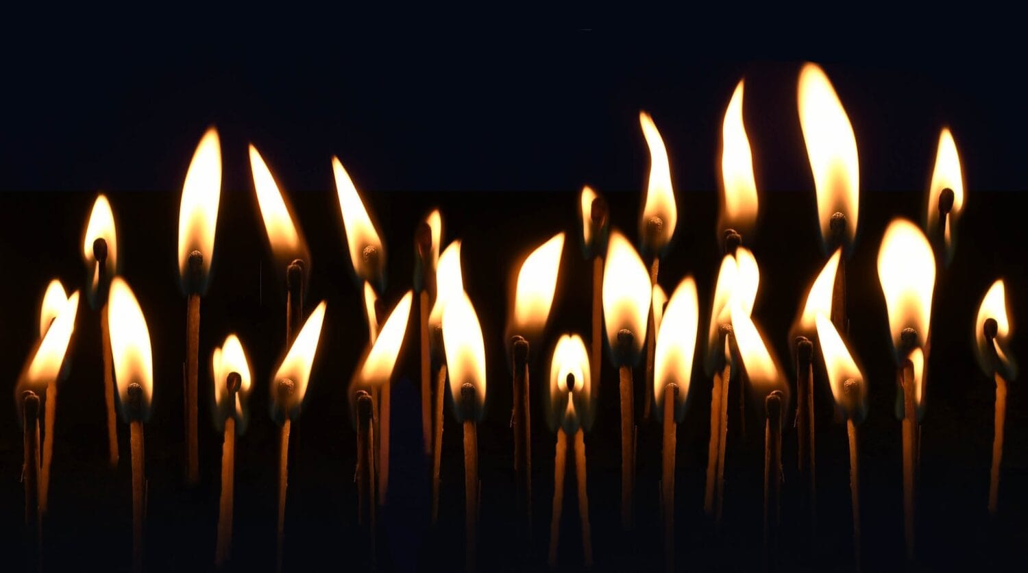 Många tända ljus mot en mörk bakgrund.